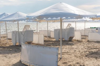 Deniz sahilinde beyaz şemsiyeler ve şezlonglar..