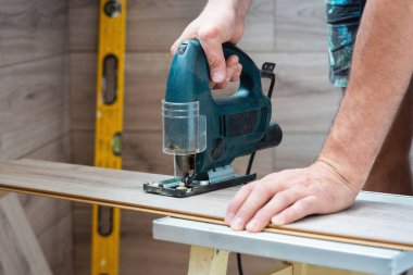 Yapboz testeresi kullanan bir işçi lamine tahtalar kullanıyor..