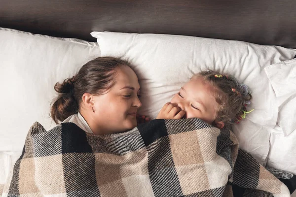 Young mother with daughter sleeping in bed.