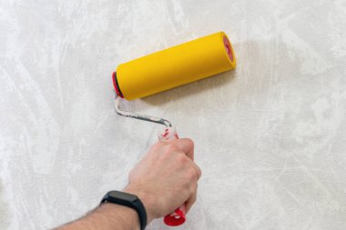 Duvar kağıdını düzeltmek için rulo yapan bir adam eli. Dairenin duvar kağıtlarını hazırlıyorum..