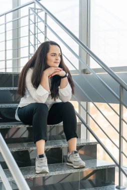 Güzel bir kızın portresi merdivenlerde oturuyor ve bir şeyler düşünüyor..