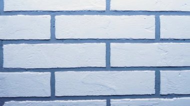 Duvarda beyaz tuğla şeklinde dekoratif alçı var.