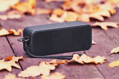 Sonbahar zamanı tahta masada müzik dinlemek için taşınabilir kablosuz hoparlör.