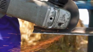 Bir işçi, metali açı öğütücüsüyle keser. Metal kesildiğinde kıvılcımlar uçuşur