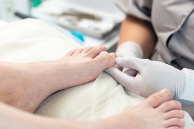 Doktor pediatrist ameliyattan önce hastanın ayak tırnağını muayene eder..