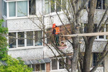 Bila Tserkva, Ukrayna, Mayıs 04, 2023: Kentteki işçiler vinç üzerinde dururken ağaçları testere ile kestiler.
