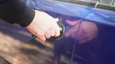 Bir adamın eli anahtarla arabanın kapısını açar.