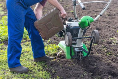 Bir adam benzin tüp üzerinden Kültivatör tank içine dökülen..