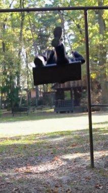 Küçük kız parkta salıncakta sallanıyor.