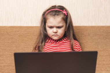 Dizüstü bilgisayarını eğlence ya da eğitim amaçlı kullanan güzel bir kız. Koltukta oturuyor..