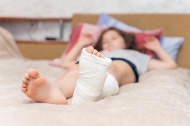 Kırık bacağı alçıdan yapılmış küçük bir kız yatakta yatıyor..