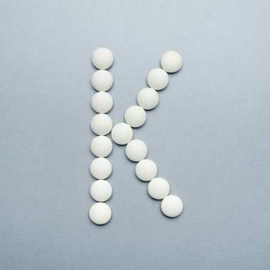 Gri arkaplandaki beyaz haplardan yapılmış k harfi..