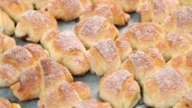 Ev yapımı kekler, fırında pişmiş taze bir tepside süzme peynirli çörekler üzerine pudra şekeri serpiştirilmiş.