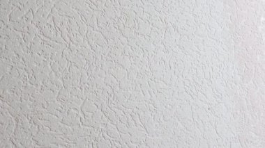 Bir işçi bir silindirle duvarı pembeye boyar.