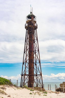 An old rusty abandoned lighthouse and a ruined building on the Dzharylhach island on the Black Sea coast. clipart