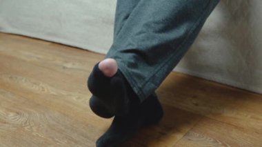 Eski siyah çoraplı bir adamın ayakları, birinin ayak başparmağında bir delik var.