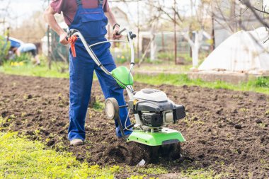 Tarımla uğraşan bir adam sebze ekimi için ekiciyle toprağı sürüyor..