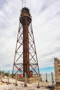 An old rusty abandoned lighthouse and a ruined building on the Dzharylhach island on the Black Sea coast. clipart