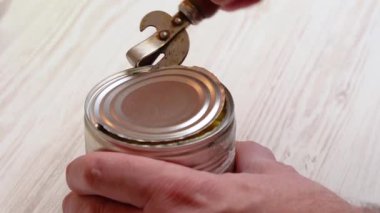 Bir adamın elleri eski bir konserve açacağıyla bir kutu mısırı açıyor.