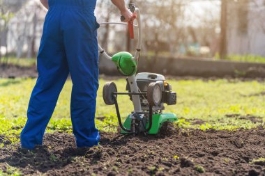 Tarımla uğraşan bir adam sebze ekimi için ekiciyle toprağı sürüyor..