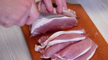 Kasap ahşap tahtada mutfak bıçağıyla et filetosu kesiyor.
