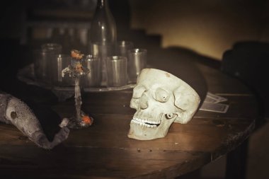 İnsan kafatası, eski şamdan, karanlık kasvetli odada ahşap masada gözlüklü şişe..