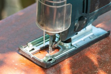 Bir marangoz elektrikli bir yapbozla tahtayı keser..