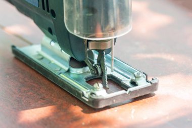 Bir marangoz elektrikli bir yapbozla tahtayı keser..