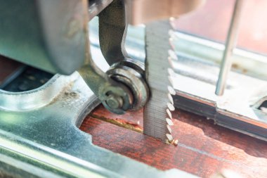 Bir marangoz elektrikli bir yapbozla tahtayı keser..