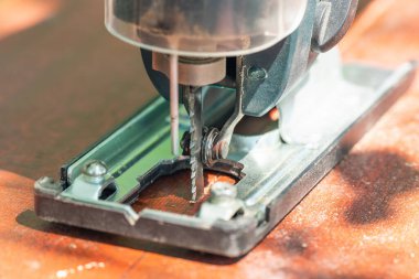 Bir marangoz elektrikli bir yapbozla tahtayı keser..