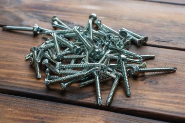 Tahta bir masanın üzerinde kendi kendine dokunan bir sürü vida..