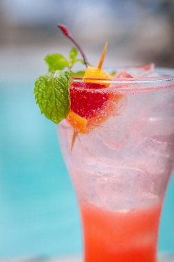 Singapur kokteyllerini limon dilimi, nane filizi ve vişne kokteyli ile süslenmiş bardakla kapat. Cam, ahşap bir tepside durur.