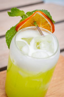 Yakın görüş, Midori ekşi kokteyli dilimlenmiş limon ve nane yaprakları bir havuzun önünde ahşap tahtalar üzerinde