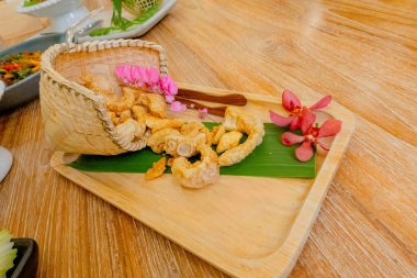 Fried pork rinds in a Bamboo basket on wooden tray clipart