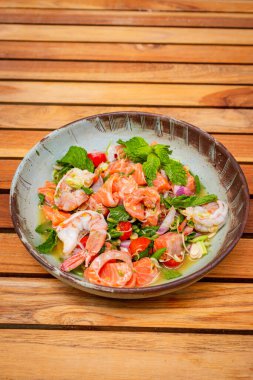Baharatlı somon ve karides salatası ahşap kalaslarda.