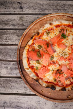 Manzara, somonlu pizza, ahşap tepside.