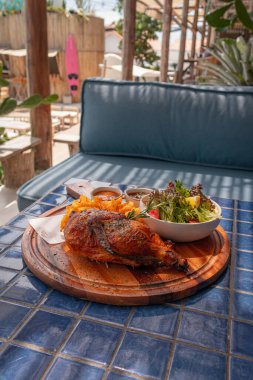 Fırında pişirilmiş yarım tavuk, karışık bahçe salatası ve ahşap tepside patates kızartması.