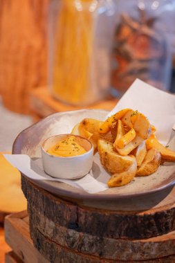 Dalış peyniri ve tartar soslu kızarmış patates dilimleri yuvarlak tabakta.