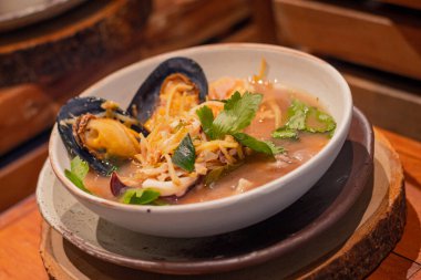 Tayland çorbası, Tayland otları ve deniz ürünleri kasede, ahşap servis tahtasının üzerinde. Tayland yemeğinin adı 