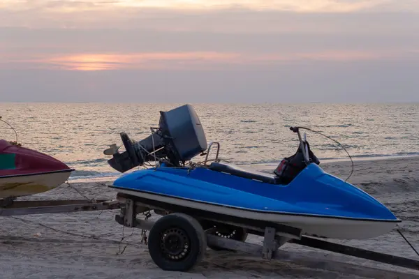 Chonburi, Tayland 'da okyanus ve günbatımı olan kumlu bir sahilde park etmiş bir karavanda mavi jet ski.