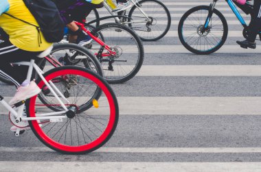Çizgili bir yoldan geçen bir grup bisiklet, bisiklet tekerleklerine odaklanmış.
