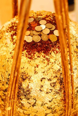 Round stones covered with gold leaf with coins on it, the stones buried to the ground in buddhist Thai temple. Thai called LUUK NIMIT clipart