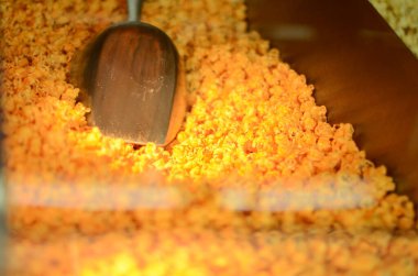 Büyük miktarda turuncu patlamış mısırın arasına sinemanın lobisindeki makineye yerleştirilmiş bir haber.