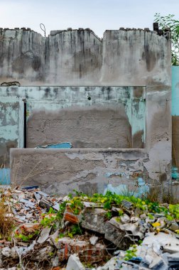 Parçalanmış beton ve soyulmuş boyayla kısmen tahrip edilmiş bir duvar.