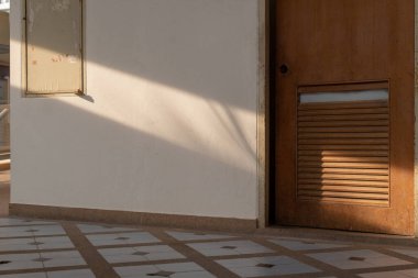 Ahşap kapılı ve küçük pencereli bir duvarın olduğu basit bir iç mekan.