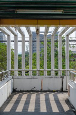 Uzun, dikey, eşit aralıklı sütunları ve üst iskeleti olan bir yaya üst geçidi.