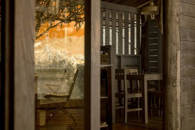 Kızıl ötesi fotoğrafçılık, ahşap bir yapının camındaki yansıma, muhtemelen bir kulübe veya kafe, masalar ve sandalyeler kurulmuş.