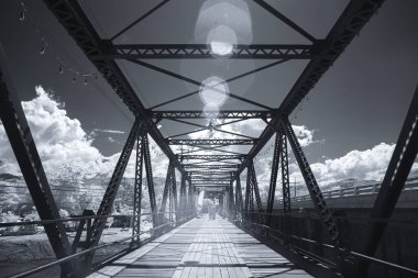 Infrared photography, a metal bridge with a sturdy framework and a wooden walkway at Black bridge, Lampang, Thailand clipart