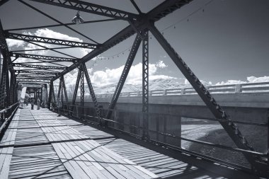 Infrared photography, a metal bridge with a sturdy framework and a wooden walkway at Black bridge, Lampang, Thailand clipart