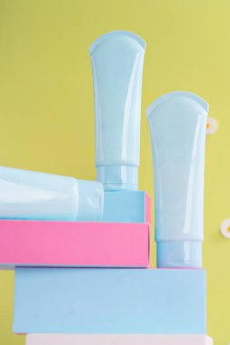 Pastel renkli kutuların üzerine konmuş üç adet açık mavi losyon tüpü.